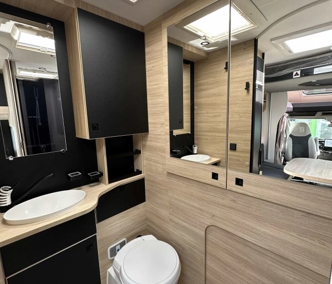Salle de bain moderne dans un camping-car avec lavabo et toilettes intégrés.