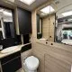 Salle de bain moderne dans un camping-car avec lavabo et toilettes intégrés.