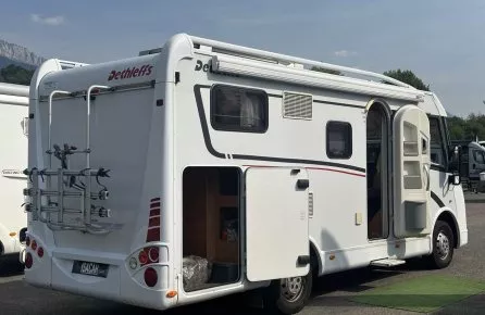 Camping-car Dethleffs stationné avec porte ouverte et porte-vélos à l'arrière.