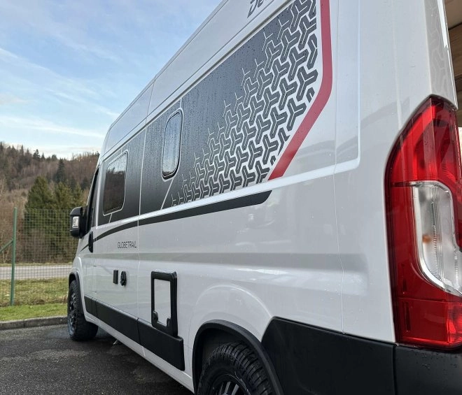 Camping-car Dethleffs Globevan stationné sur un parking, vue arrière latérale.
