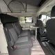 Intérieur d'un van aménagé avec sièges et table pliante, idéal pour le camping.