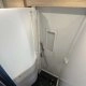 Douche compacte avec parois blanches et sol noir dans un camping-car moderne.