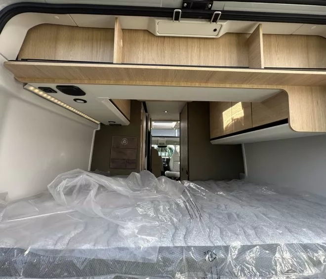 Intérieur d'un camping-car avec lit et rangements en bois clair