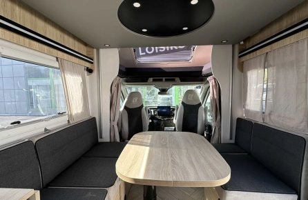 Intérieur spacieux d'un camping-car moderne avec table et banquettes grises