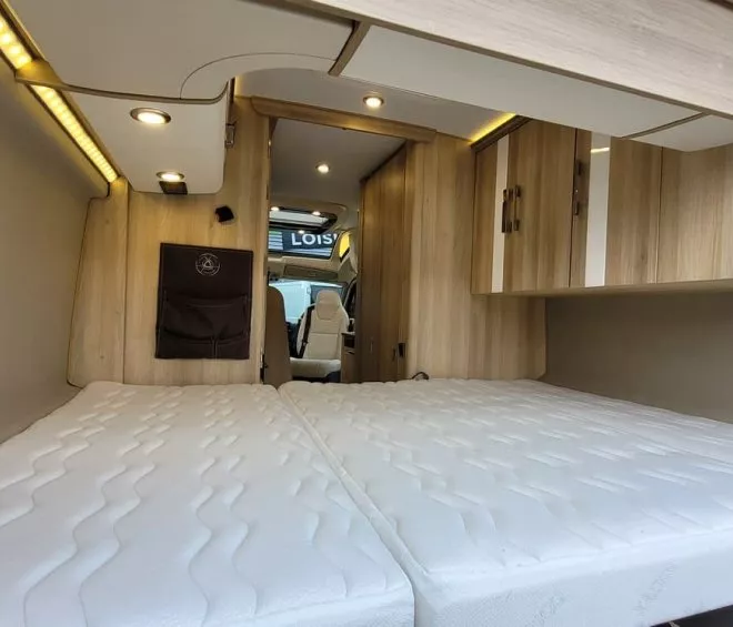 Intérieur d'un van aménagé avec lit et rangements en bois clair