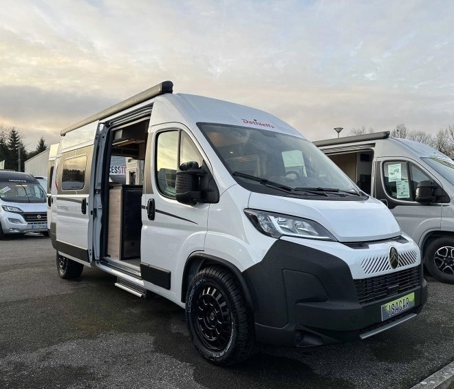Camping-car blanc Dethleffs avec porte ouverte sur un parking