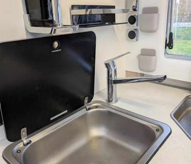 Évier en acier inoxydable avec robinet moderne dans une cuisine compacte de camping-car.