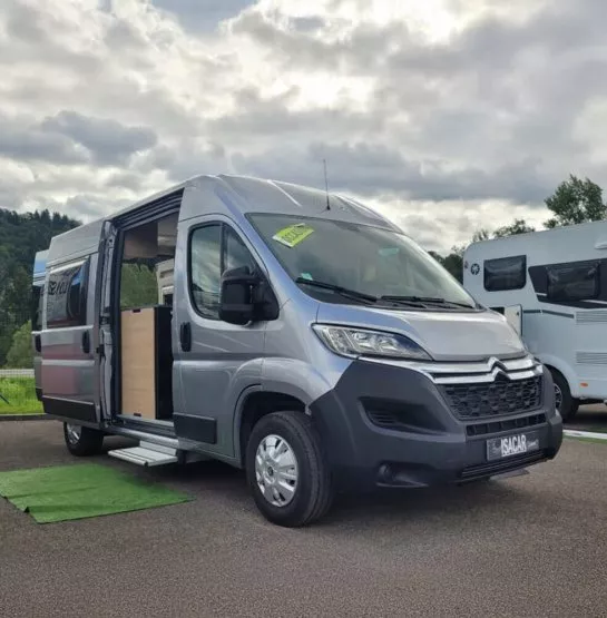Fourgon aménagé Citroën gris stationné sur un parking, porte latérale ouverte