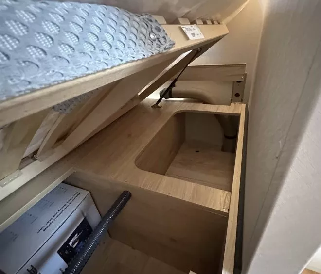 Coffre de rangement en bois sous un lit avec matelas relevé