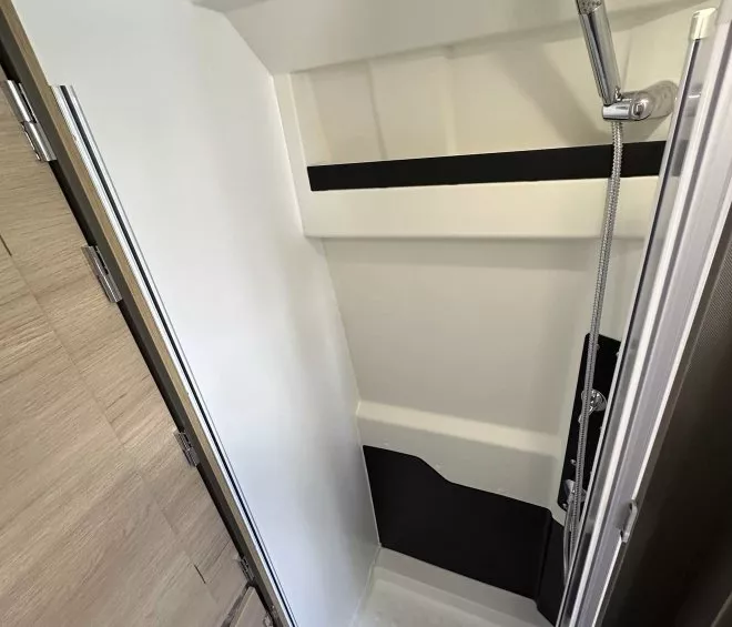 Douche moderne avec parois blanches et pommeau chromé dans un espace restreint