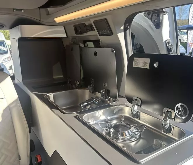 Cuisine intégrée dans un van aménagé avec évier et réchaud.
