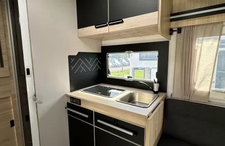 Intérieur moderne de cuisine de camping-car avec évier et rangements noirs et bois.