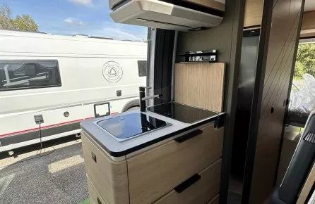 Intérieur moderne d'un camping-car avec cuisine équipée et rangements en bois clair.