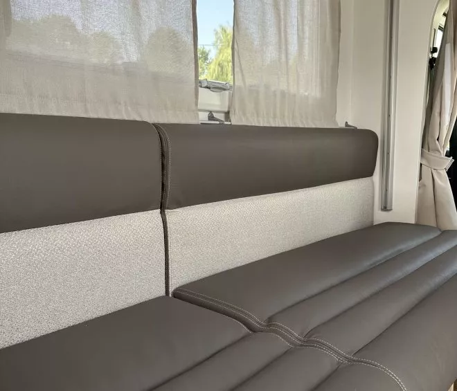 Banquette en cuir dans un camping-car avec rideaux et fenêtre ouverte