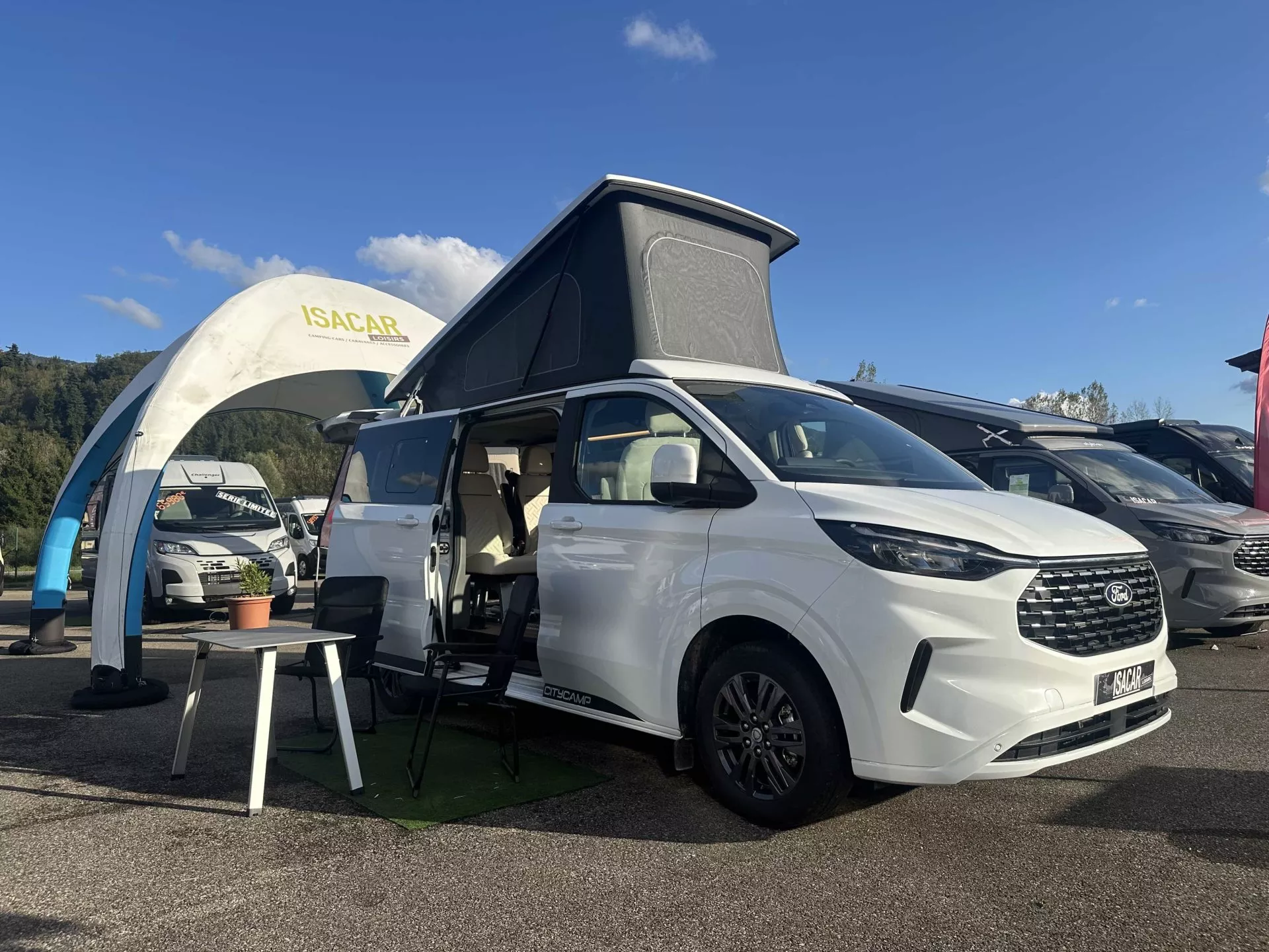 Camping-car Ford blanc exposé chez Isacar sous un ciel bleu