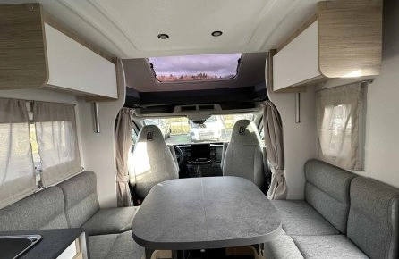 Intérieur d'un camping-car moderne avec table et banquettes grises