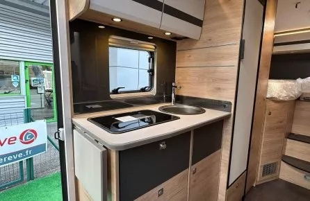 Cuisine moderne d'un camping-car avec évier, plaques de cuisson et rangements en bois clair.