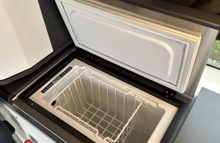 Réfrigérateur intégré dans un véhicule aménagé avec panneau de contrôle numérique.