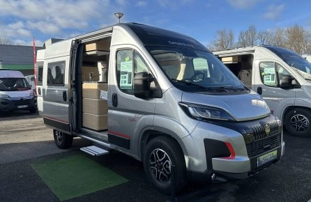 Camping-car gris avec porte latérale ouverte sur un parking