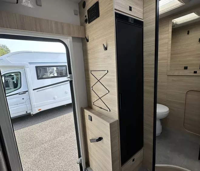 Intérieur d'un camping-car moderne avec salle de bain et mobilier en bois clair.