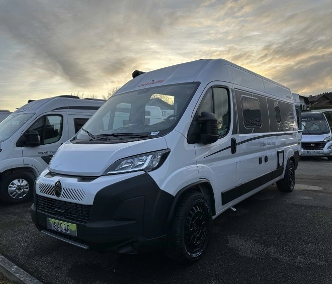 Camping-car blanc stationné sur un parking au crépuscule