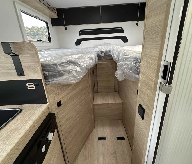 Intérieur d'un camping-car avec lits jumeaux et mobilier en bois clair