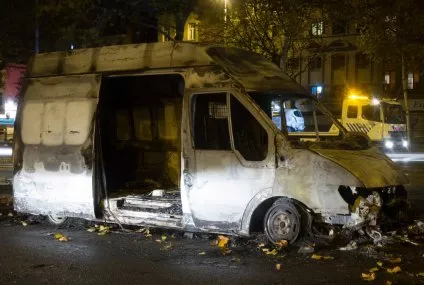 Fourgon incendié sur une route la nuit, avec dépanneuse en arrière-plan