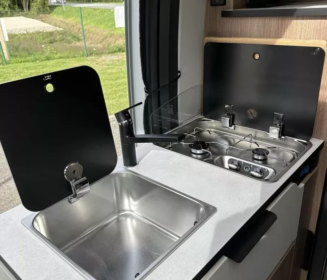 Cuisine compacte de camping-car avec évier et plaque de cuisson à gaz.