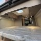 Intérieur d'un van aménagé avec lit et rangements en bois