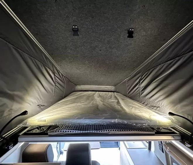 Intérieur d'un toit relevable de van aménagé avec lit intégré