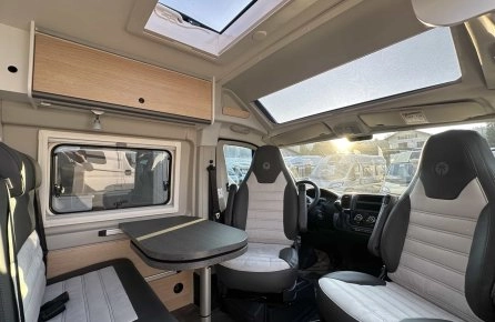 Intérieur d'un camping-car moderne avec sièges et table, éclairage naturel.