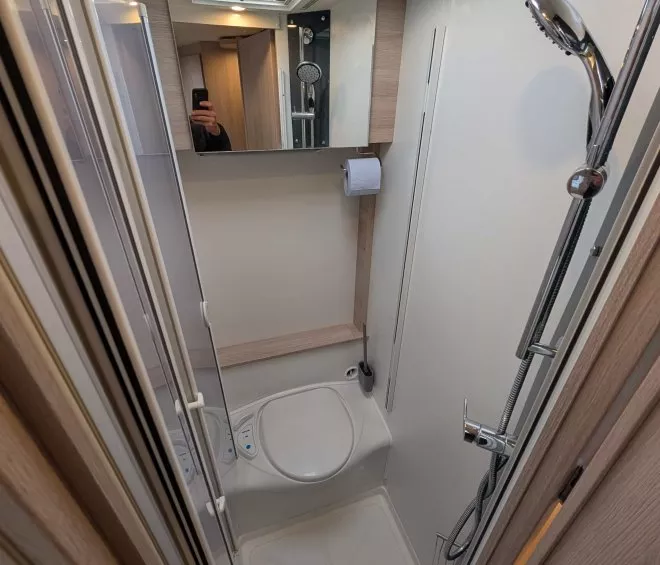 Douche compacte avec miroir et pommeau dans un espace restreint.