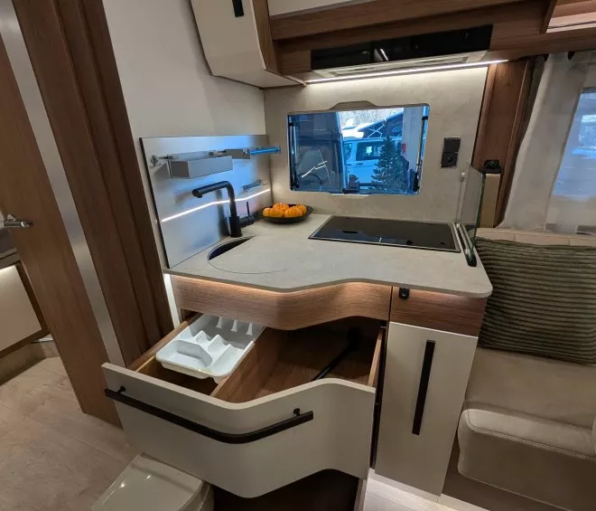 Cuisine moderne de camping-car avec évier, plaques de cuisson et rangements ouverts