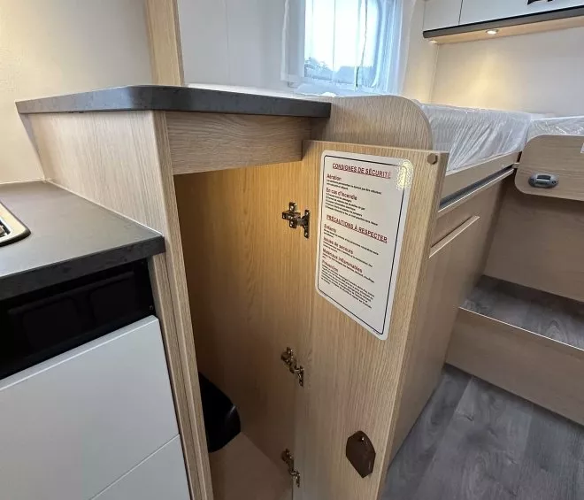 Intérieur d'une caravane avec placard ouvert et consignes de sécurité affichées.