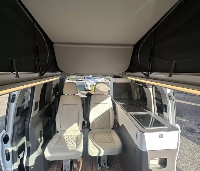 Intérieur d'un van aménagé avec sièges et kitchenette moderne