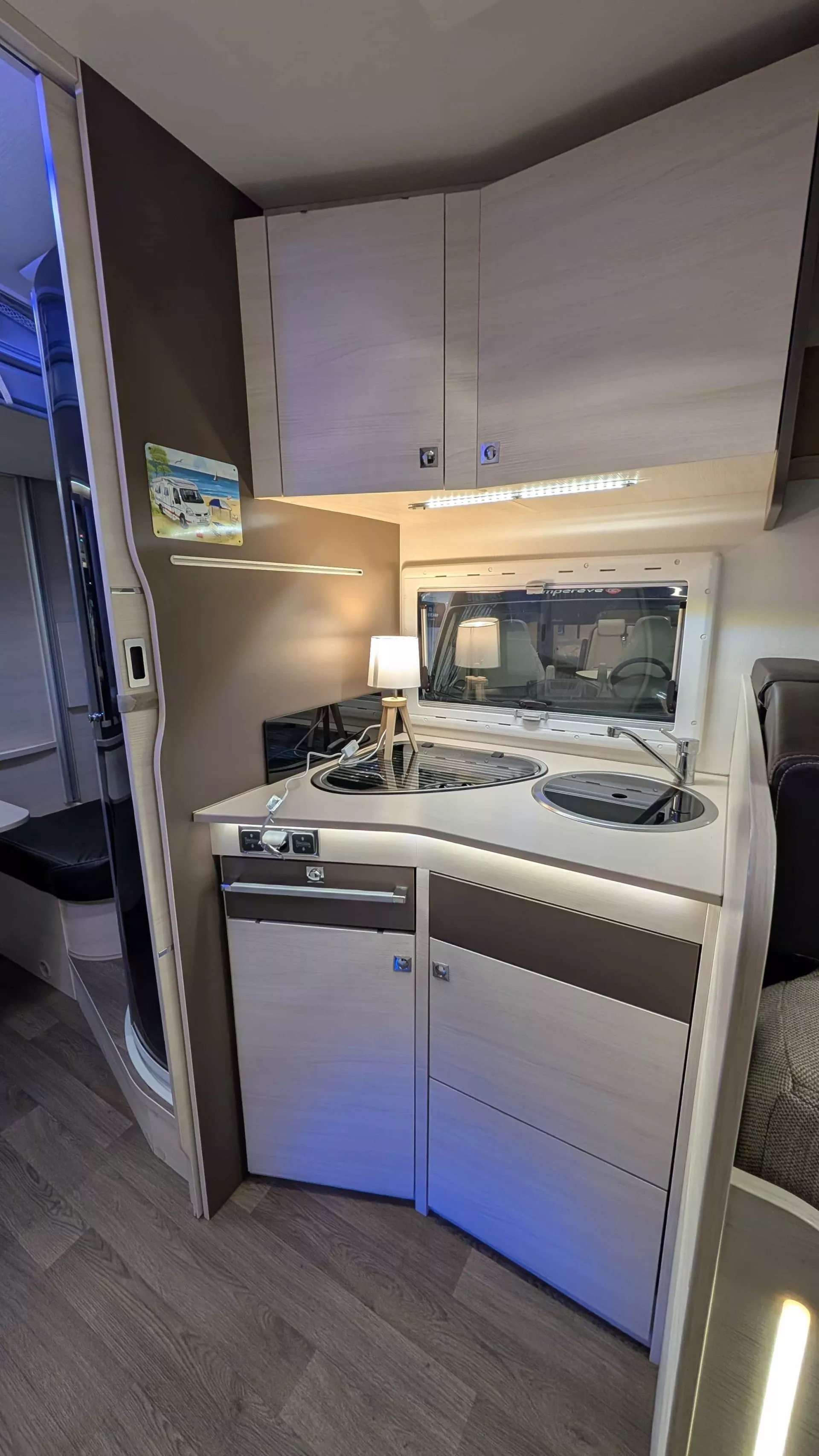 Cuisine compacte de camping-car avec évier, plaque de cuisson et éclairage intégré.