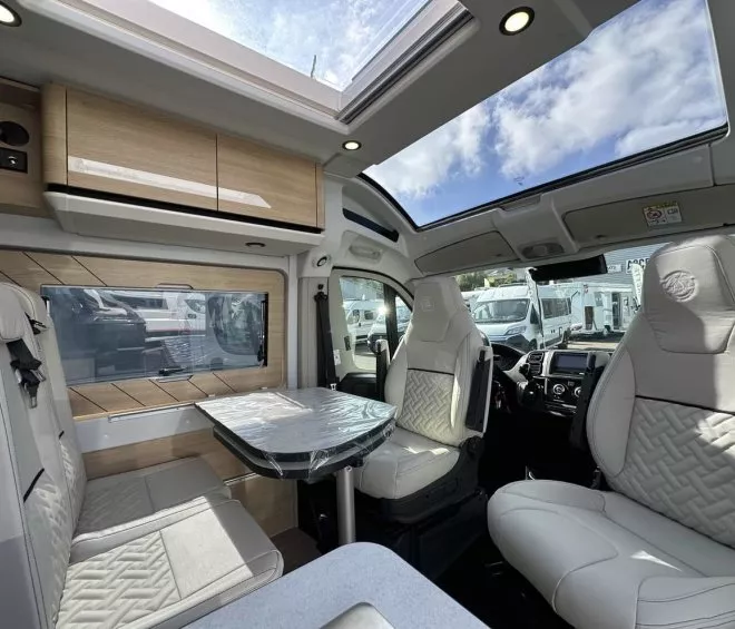 Intérieur d'un camping-car moderne avec sièges en cuir et toit panoramique.