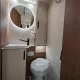 Salle de bain compacte avec lavabo, miroir rond et toilettes modernes dans un camping-car.