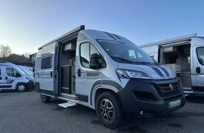 Camping-car gris stationné sur un parking, porte latérale ouverte
