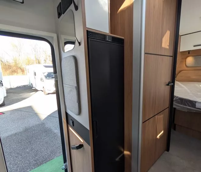 Intérieur d'un camping-car avec réfrigérateur et placards en bois clair