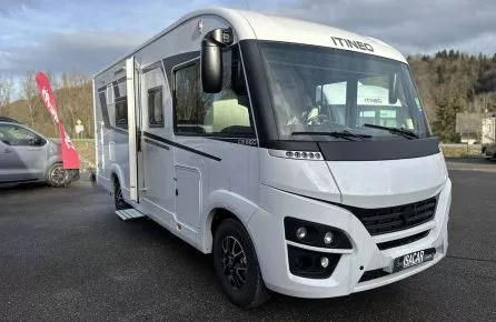 Camping-car Itineo blanc stationné sur un parking, ciel nuageux en arrière-plan.