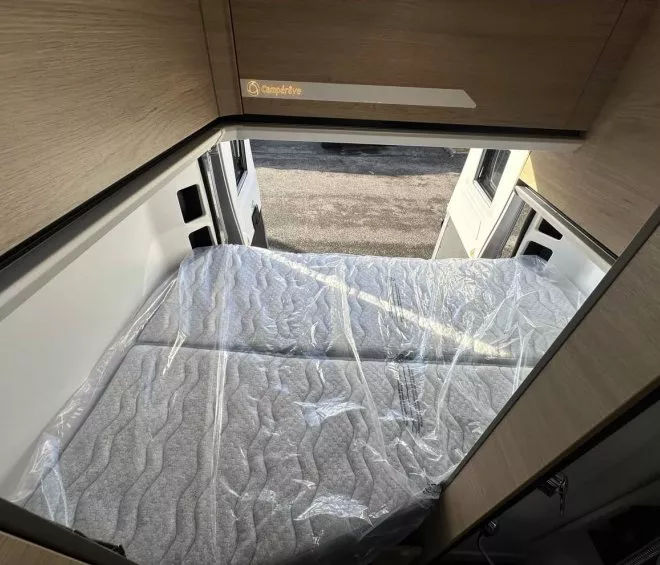 Intérieur d'un camping-car Campérêve avec lit double et rangement en bois