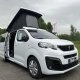 Van Peugeot blanc avec toit relevable sur un parking
