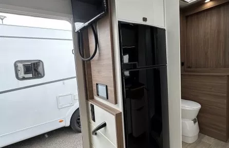Intérieur d'un camping-car moderne avec télévision et salle de bain visible.