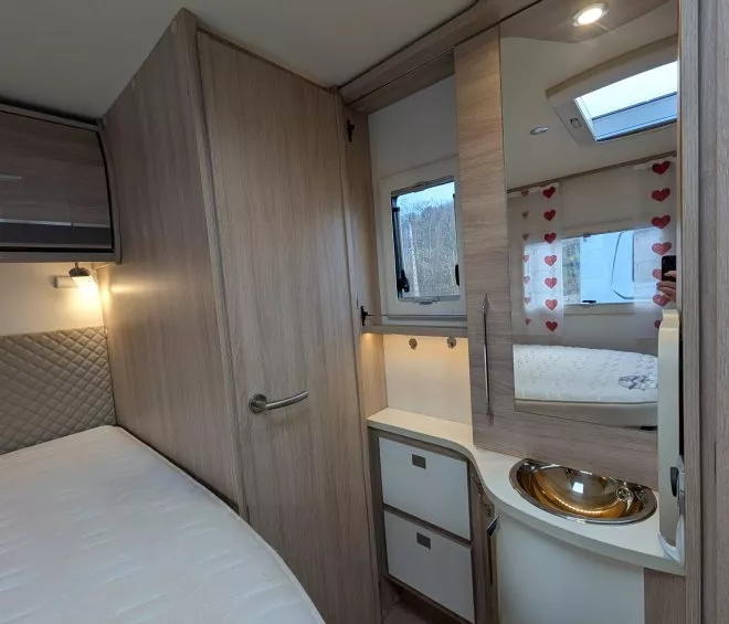 Intérieur d'une caravane avec lit, placard et lavabo moderne.