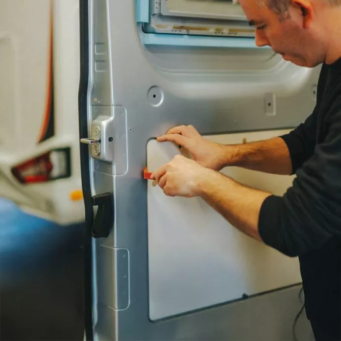 Technicien installant un panneau sur la porte d'un véhicule utilitaire
