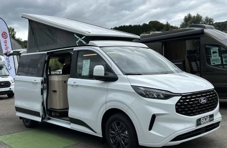 Van aménagé Ford blanc avec toit relevable sur un parking