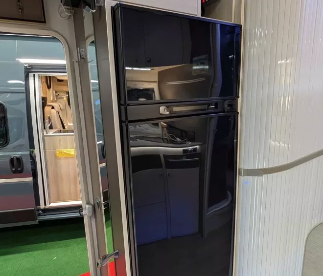 Intérieur d'un camping-car avec réfrigérateur intégré et porte ouverte sur l'extérieur