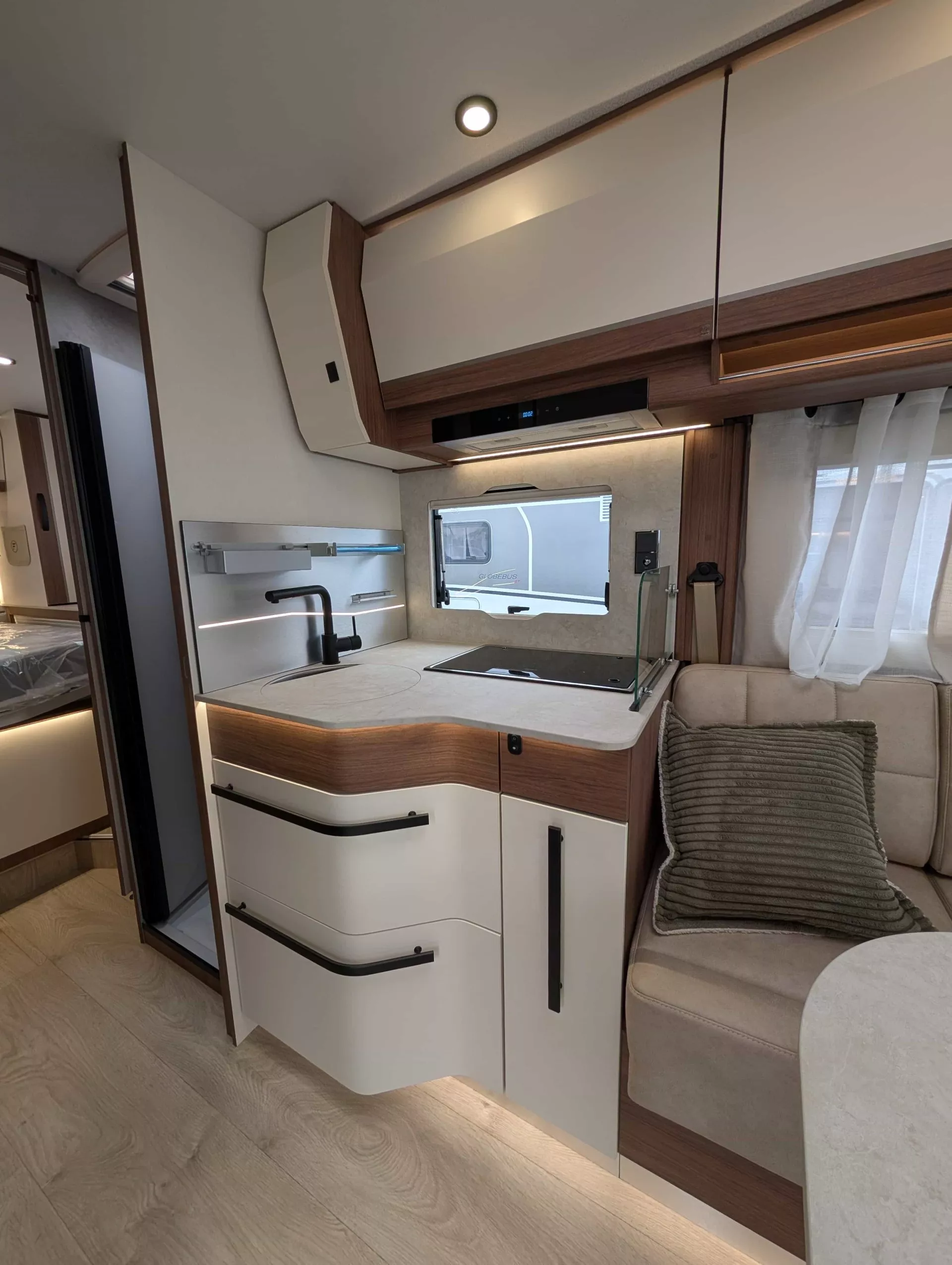 Cuisine moderne de camping-car avec évier, rangements et banquette.