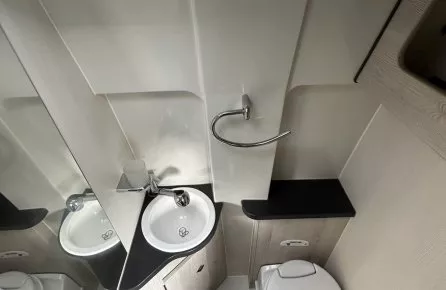 Salle de bain compacte avec lavabo, toilettes et douche dans un espace restreint.